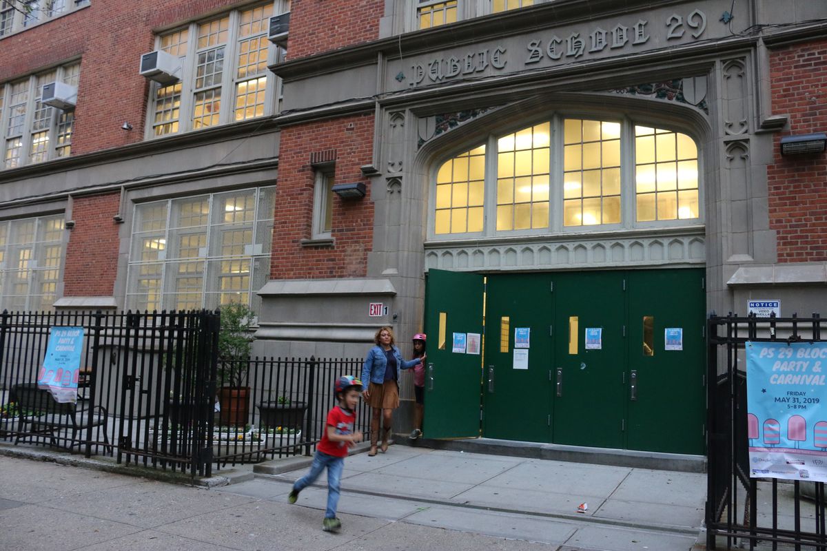 The outside front doors of P.S. 29 in Cobble Hill are pictured, with a child out front. The school is one of seven schools that could be affected by sweeping attendance zone changes proposed for Brooklyn’s District 15.