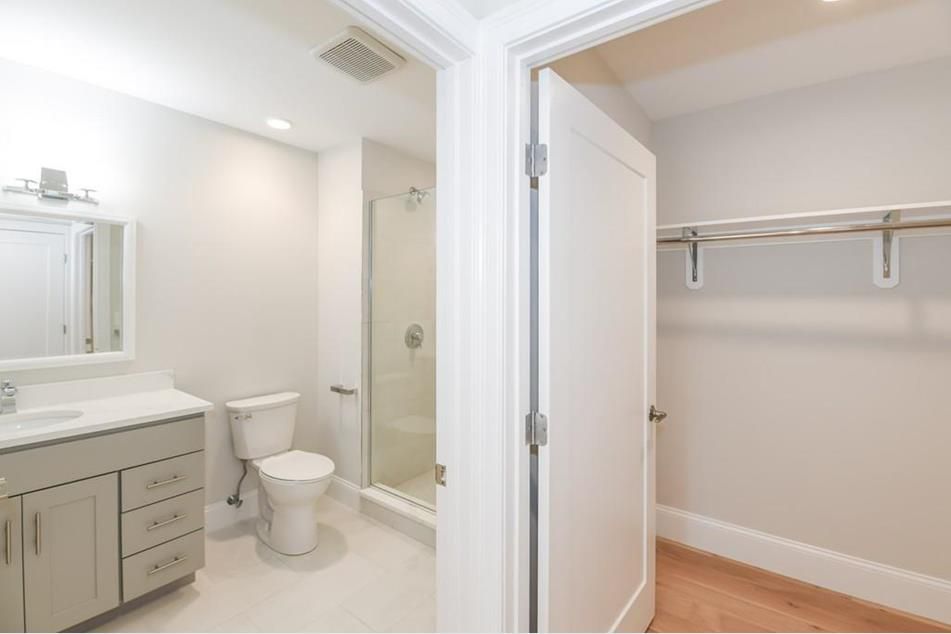 A bathroom with a large closet, and the door to the closet is open. 