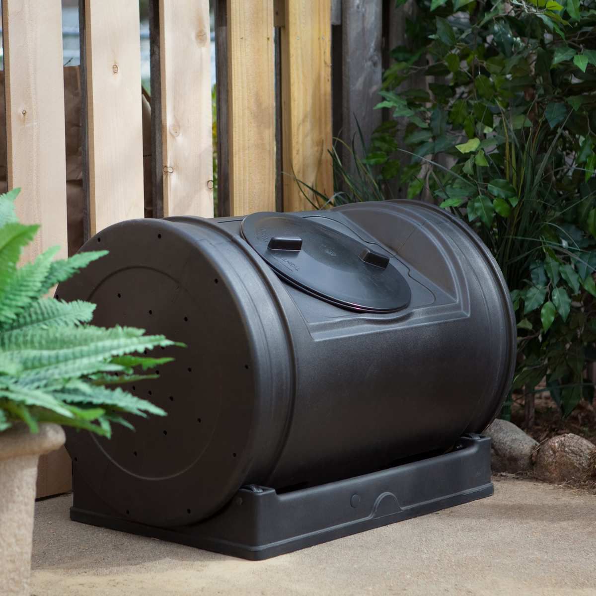 Black barrel-shaped bin in a yard.
