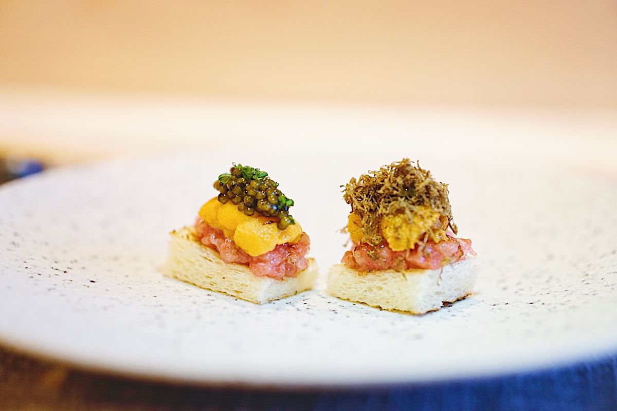 Two bites of toast with tuna, uni, and truffle on top