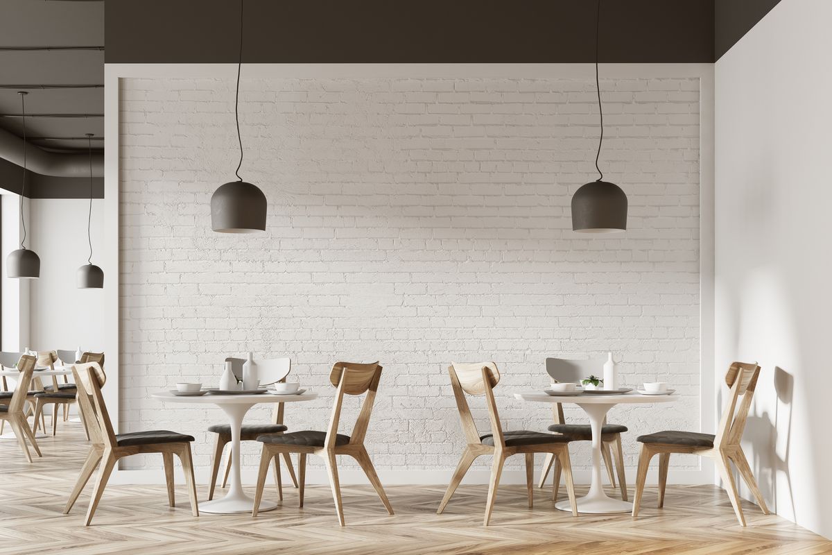Empty tables at a cafe with a modern, minimalist design and big hanging light fixtures.
