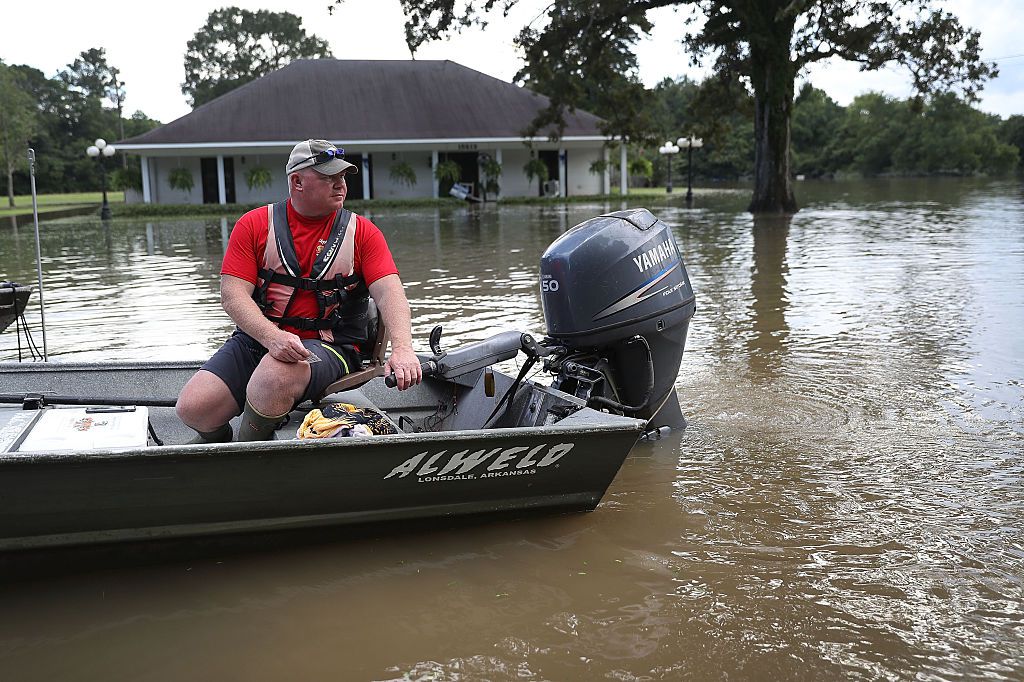 Man in a boat going down a flooded street in Louisiana.