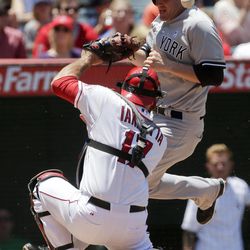 New York Yankees' Lyle Overbay, right, scores on a single by Jayson Nix past Los Angeles Angels catcher Chris Iannetta during the third inning of a baseball game in Anaheim, Calif., Sunday, June 16, 2013. 