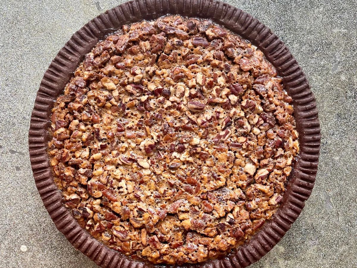 A chocolate, bourbon, pecan pie topped with pecans with a chocolate crust.