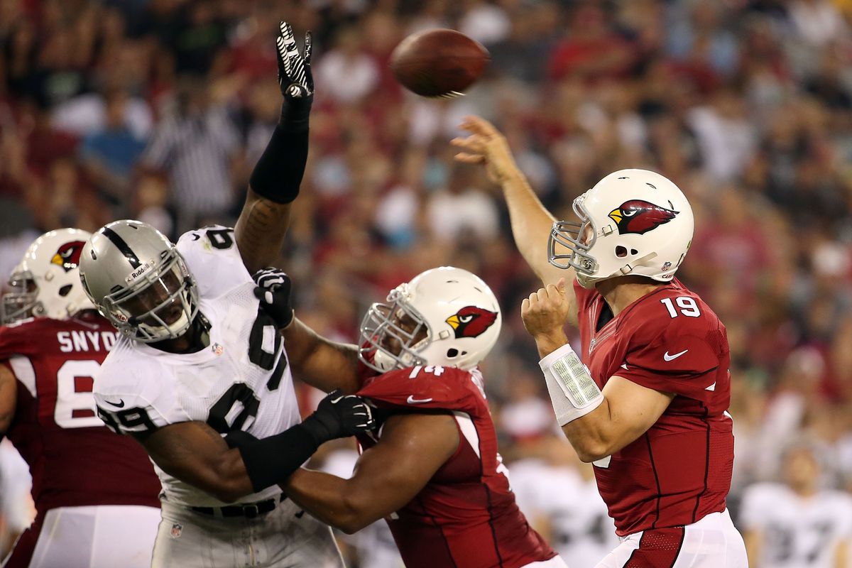 Quarterback John Skelton #19 of the Arizona Cardinals throws a pass over defensive tackle Lamarr Houston #99 of the Oakland Raiders during the NFL preseason game