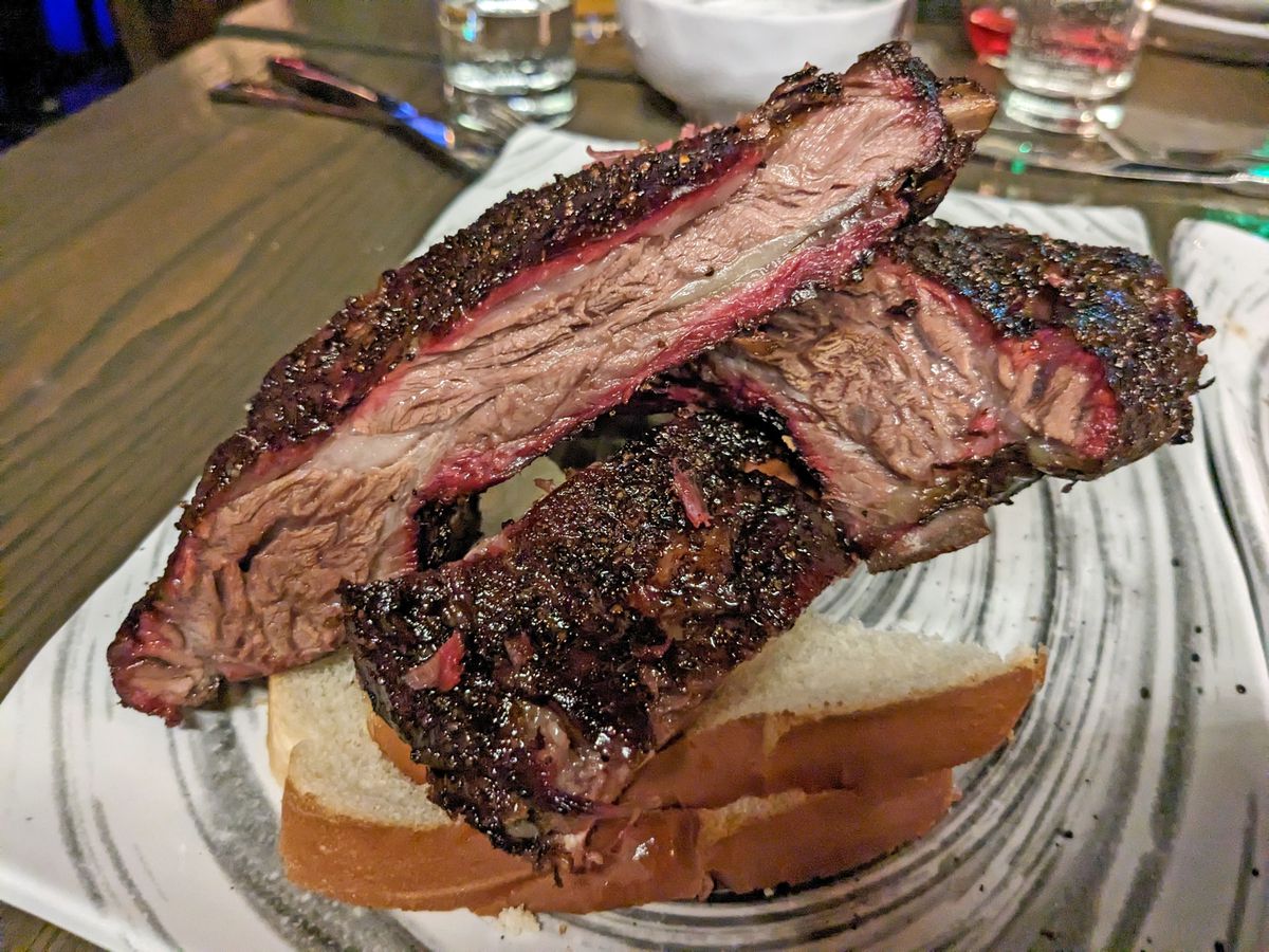 Three blackened ribs on top of white bread slices.
