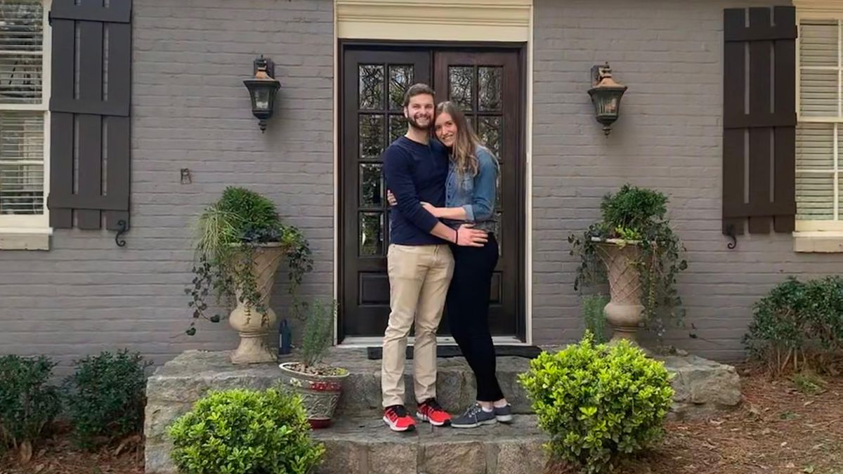 A couple stands in front of their new home in Atlanta’s Tuxedo Park neighborhood. 