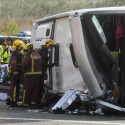 Emergency services personnel stand at the scene of a bus accident crashed on the AP7 highway that links Spain with France along the Mediterranean coast near Freginals halfway between Valencia and Barcelona early Sunday, March 20, 2016. A bus carrying university students back from a fireworks festival crashed Sunday on a main highway in northeastern Spain, killing 14 passengers and injuring 30 others, a Catalonian official said.