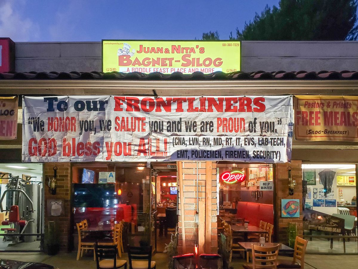 At a dimming strip mall, signs up to support frontline workers.