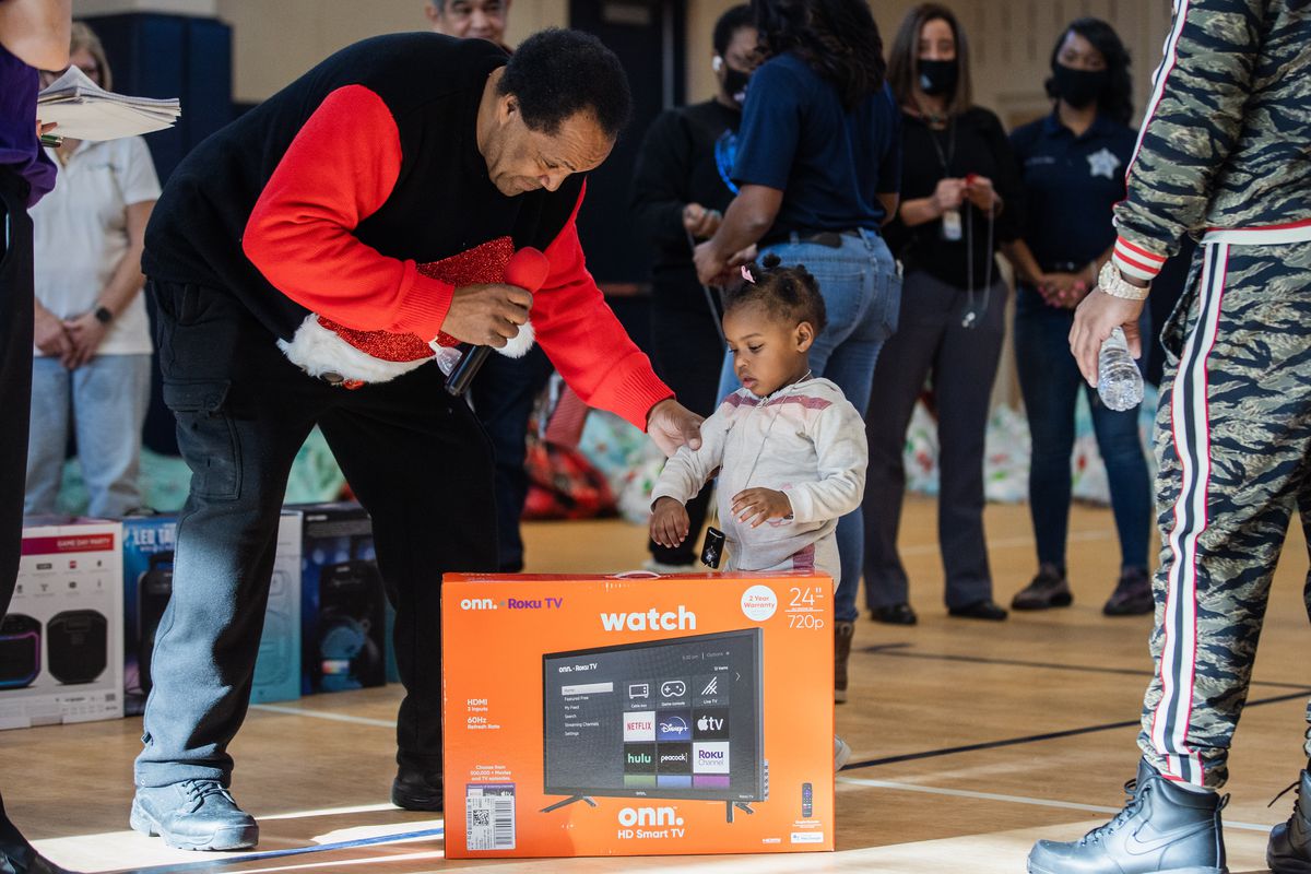 Community activist Andrew Holmes gives a television to Ella Harris, 2, who was shot in the arm, at the Salvation Army Adele and Robert Stern Red Shield Center in the Englewood.