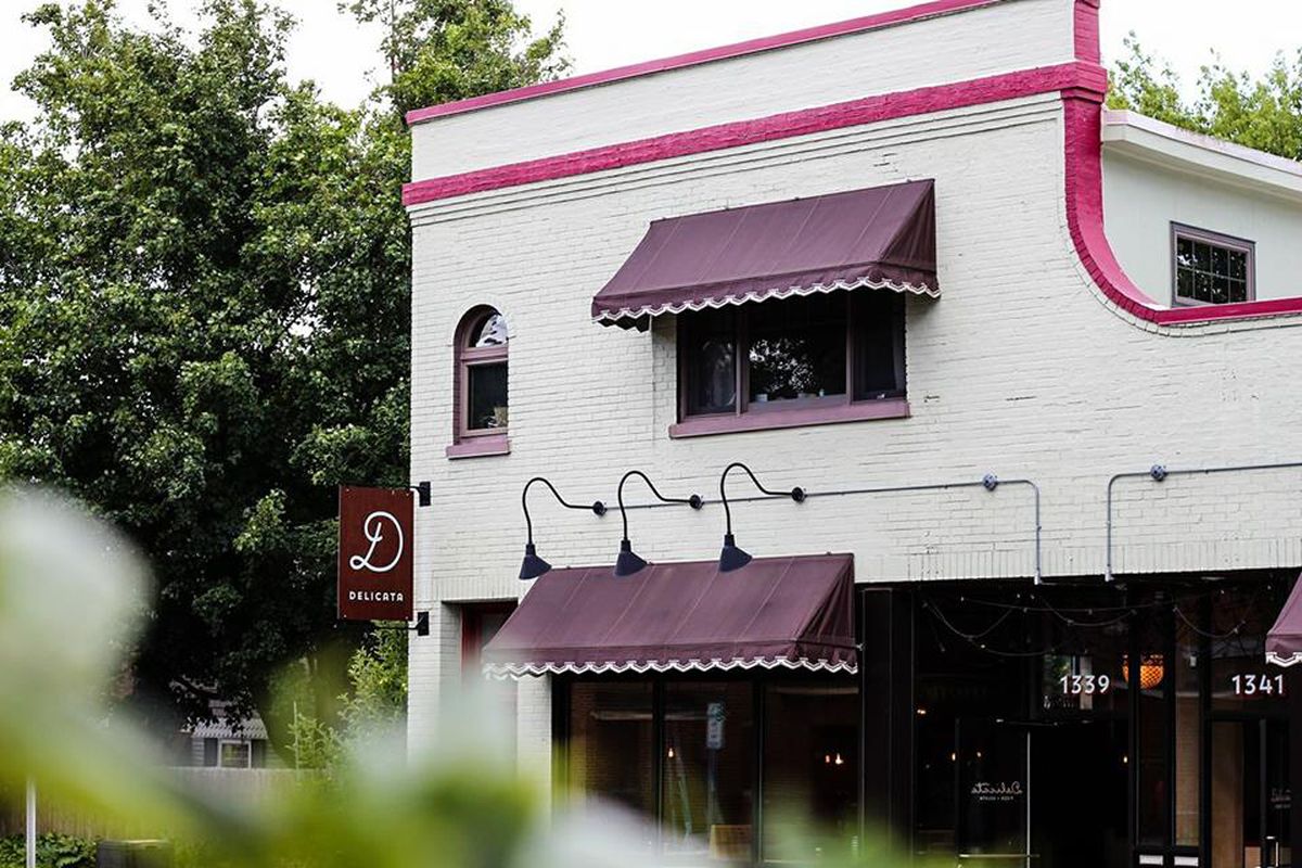 The gray exterior of the restaurant with maroon awnings