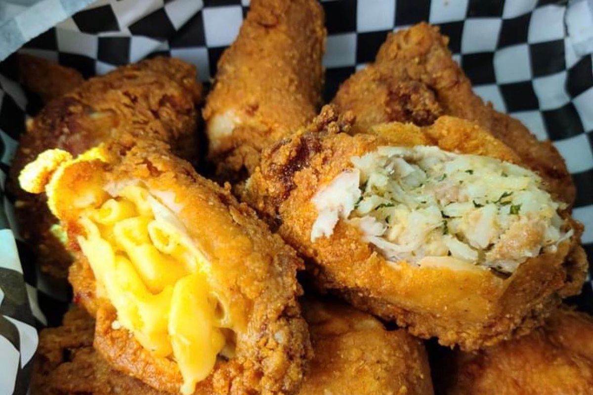 a tray of fried chicken wings stuffed with mac and cheese and boudin on black checkered paper