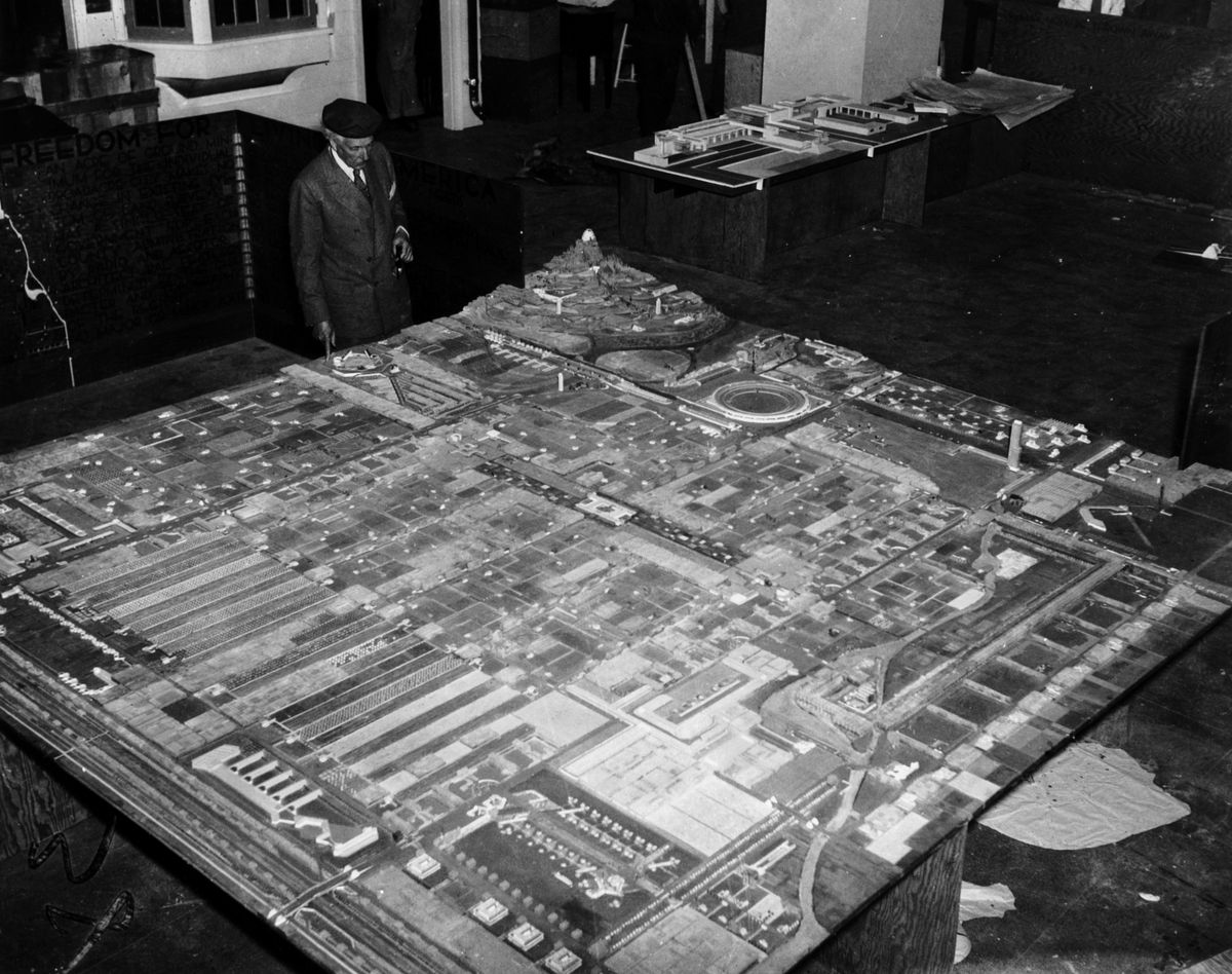 A black and white image of Frank Lloyd Wright next to his very large model. 