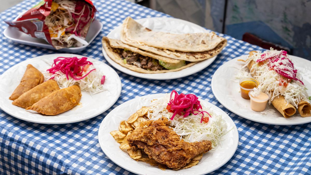 Dishes from a Honduran food truck along a table with checked blue tablecloth.