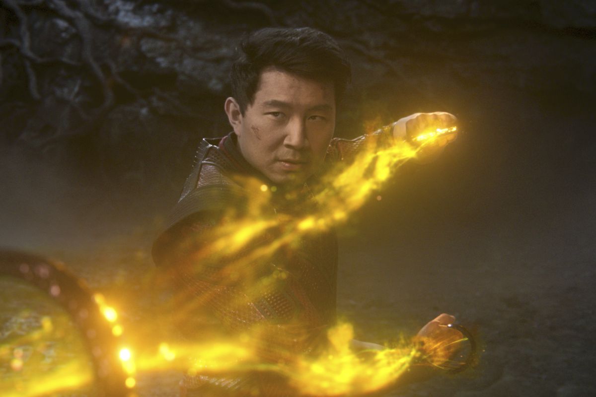 Simu Liu wields the Ten Rings, surrounded by yellow fire, as Shang-Chi in Shang-Chi and the Legend of the Ten Rings.