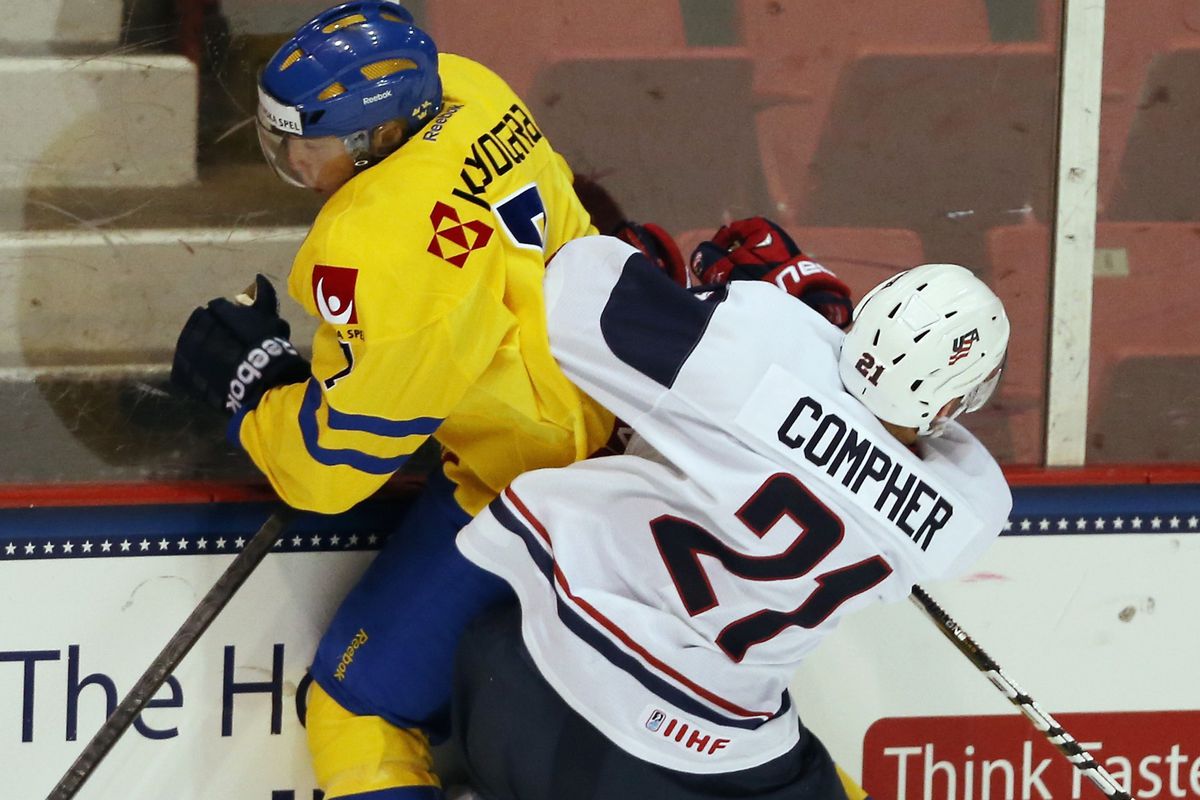 Michigan recruit JT Compher gets physical on a Swedish player.
