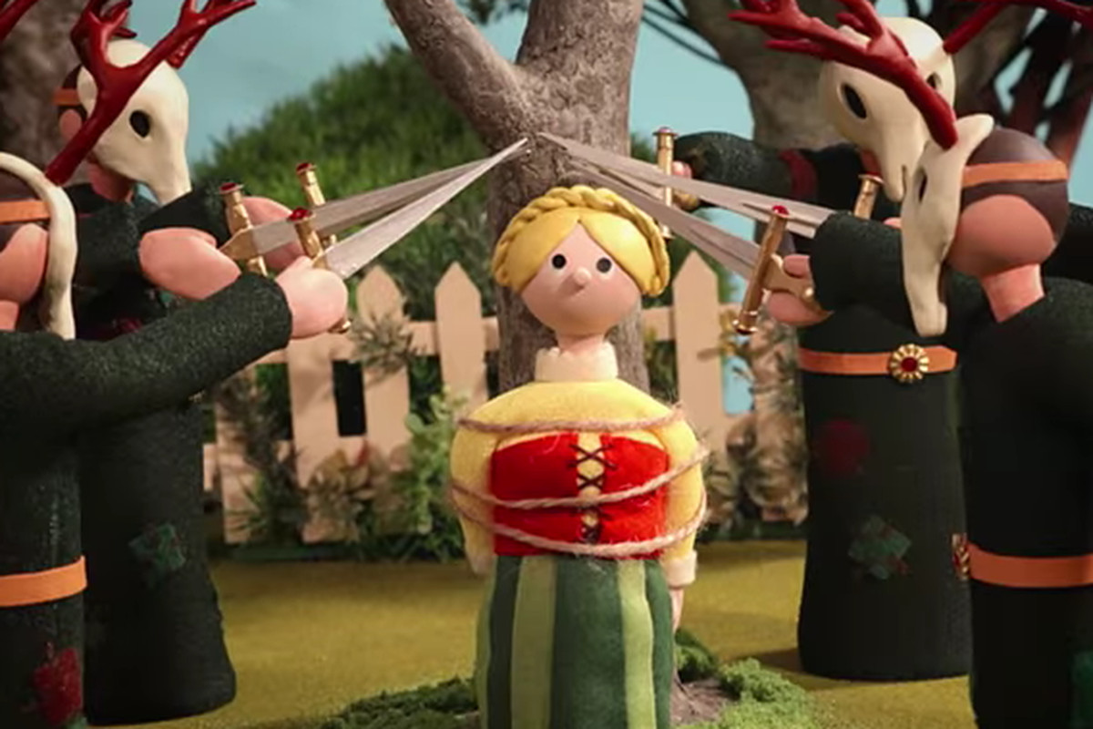 men in goat masks point swords at a woman bound to a tree in Radiohead’s Burn the Witch video