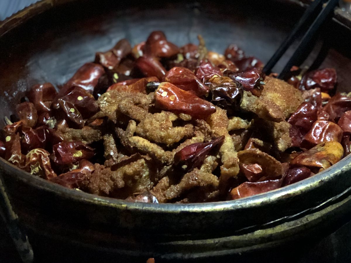 Fried crab and chiles in a dark ceramic bowl