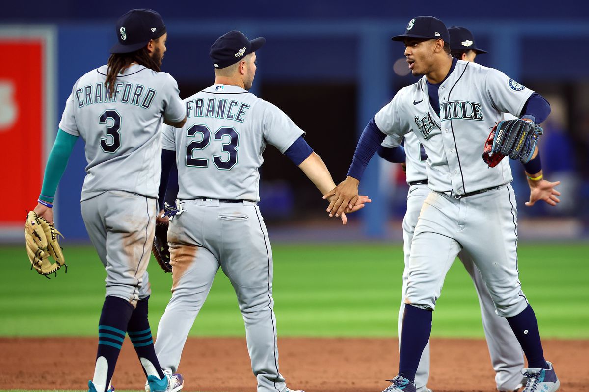 Julio Rodriguez of the Seattle Mariners celebrates the win with Ty France and J.P. Crawford following Game One of the AL Wild Card series against the Toronto Blue Jays at Rogers Centre on October 7, 2022 in Toronto, Ontario, Canada.