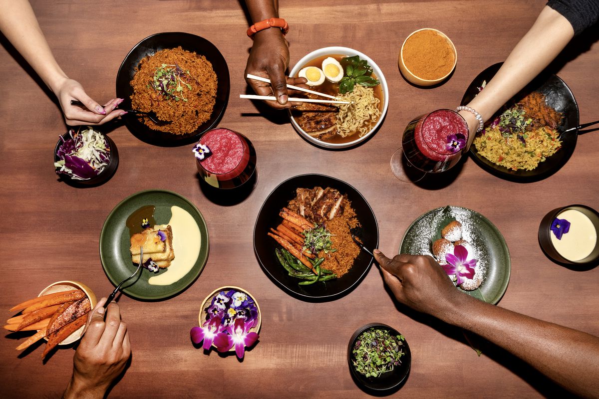 An overhead shot of a wooden table at a restaurant with bowls of rice and soup and sides.