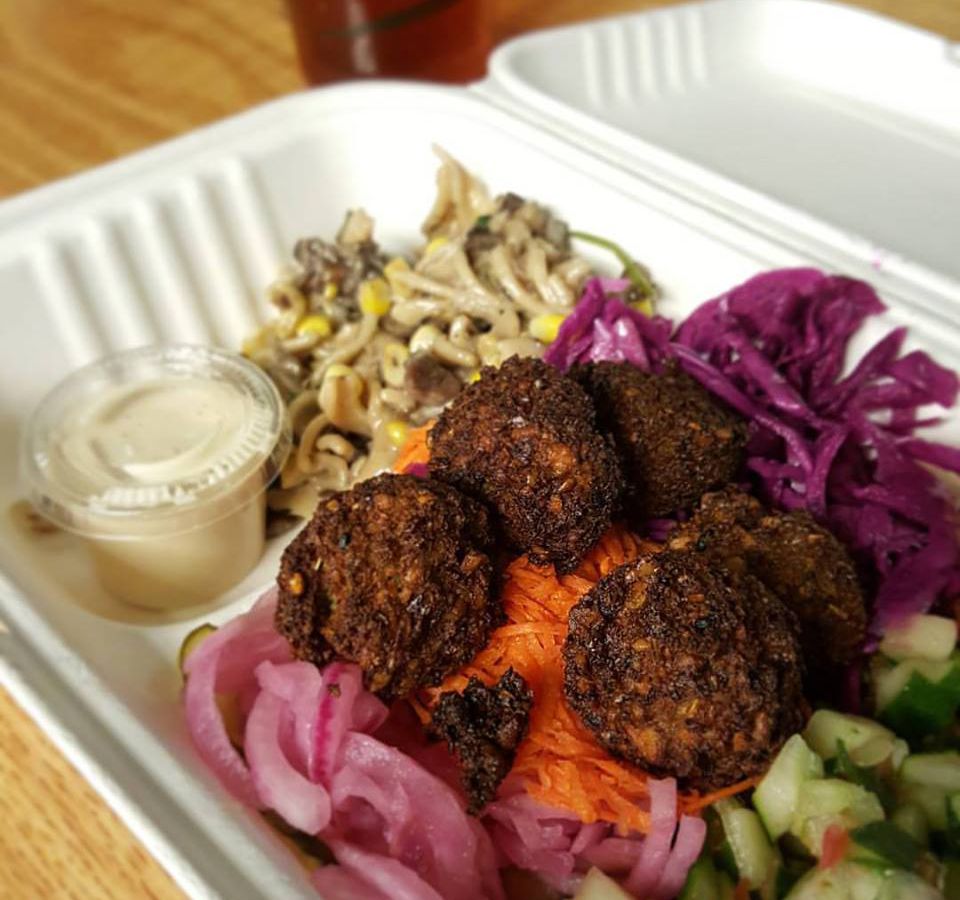 Chickpea fritters sit atop pickled vegetables in a takeout tray