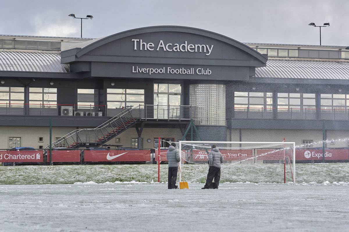 Liverpool ground staff attempting to clear snow from the pitch to enable the PL2 game at AXA Training Centre on January 23, 2021 in Kirkby, England.