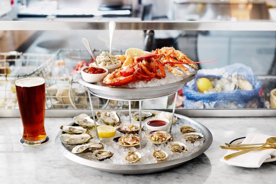 A two-level platter tower with oysters on the bottom and lobster on the top.