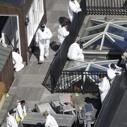 Investigators inspect the roof of a building adjacent to the area where a bomb exploded near the Boston Marathon finish line, Thursday, April 18, 2013, in Boston. Investigators in white jumpsuits fanned out across the streets, rooftops and awnings around the blast site in search of clues.  