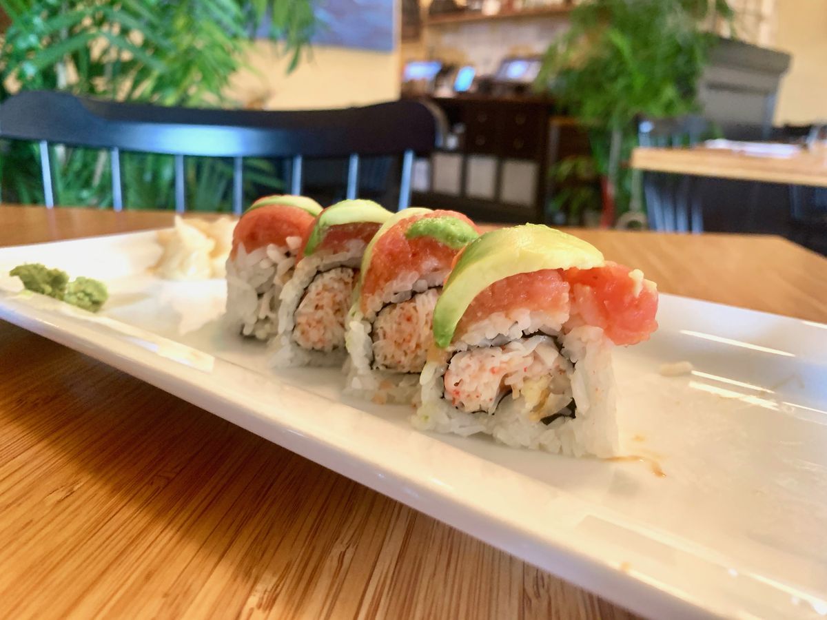 A plate with four pieces of the Tommy O’s Roll topped with spicy tuna and avocado and filled with coconut shrimp and crab.