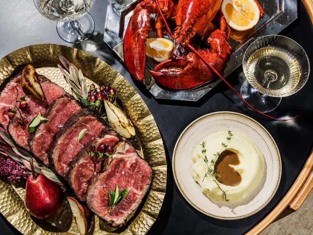 A table of sliced steak and a lobster.
