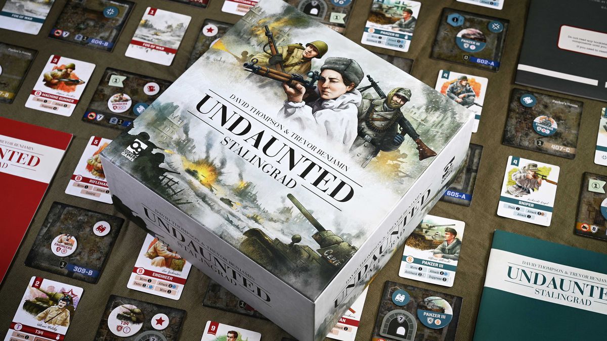 The box for Undaunted: Stalingrad rests on a table. Below it all the components for the game laid out dramatically.