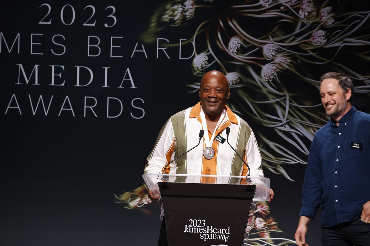 Two men accept an award with a podium.