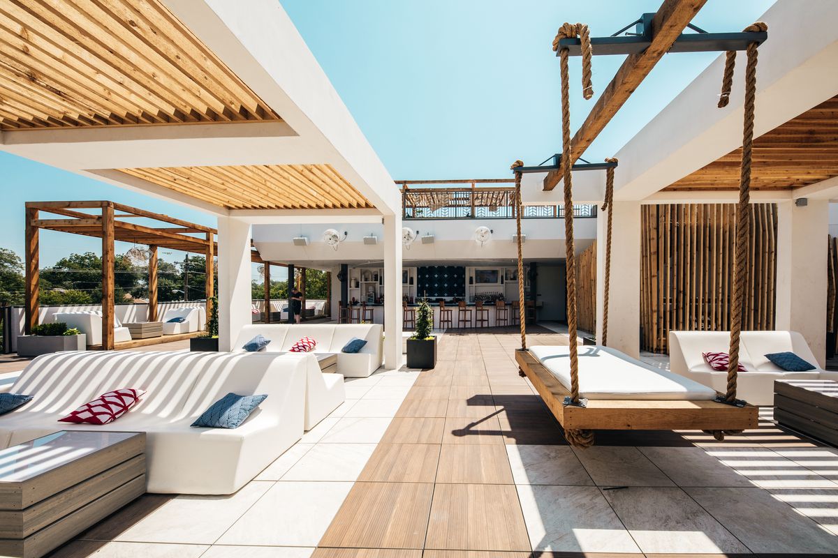 Rooftop bar with white lounge chairs and large wood swing