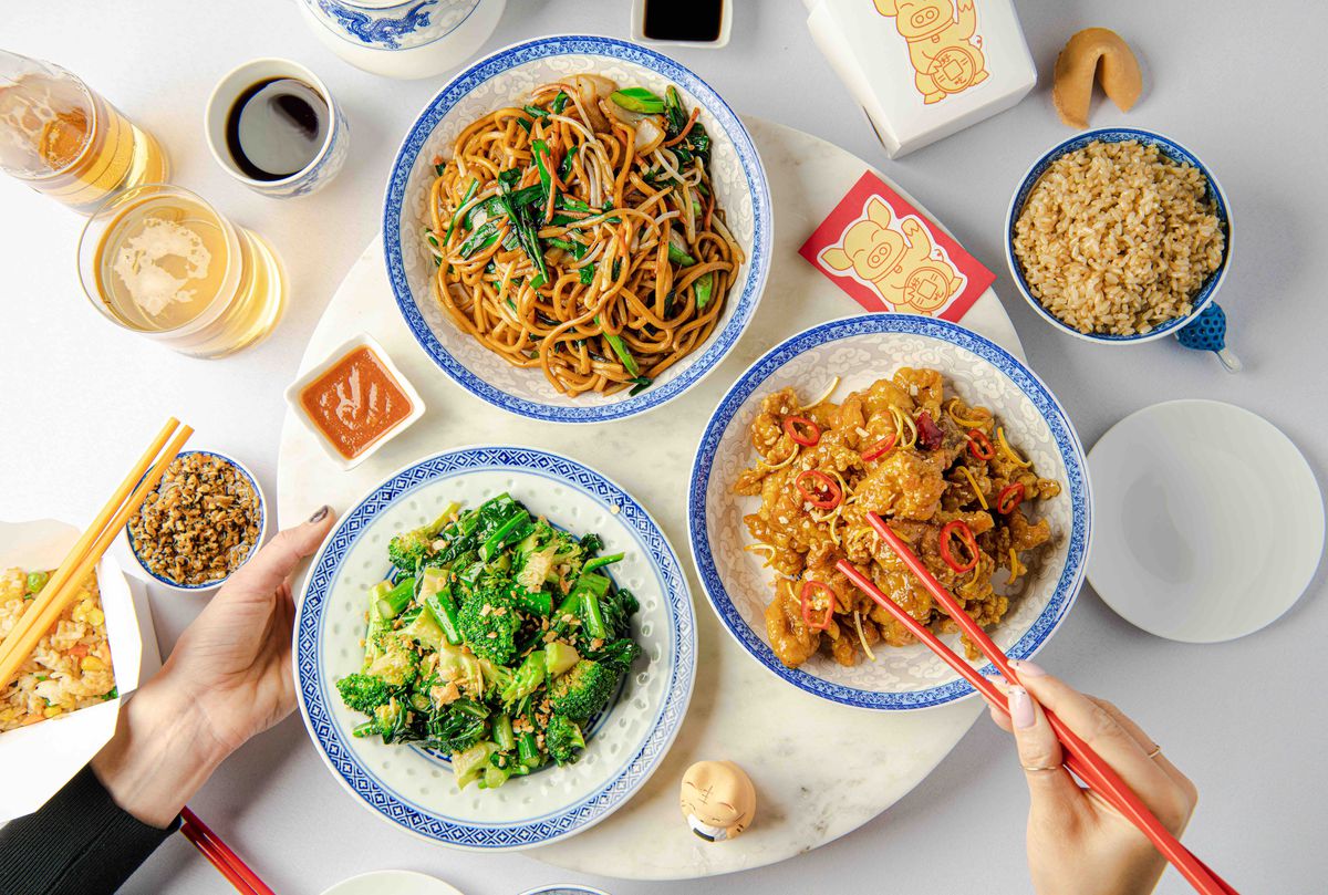 A spread of dishes from Lazy Susan: chow mein, stir-fried broccoli, and orange chicken