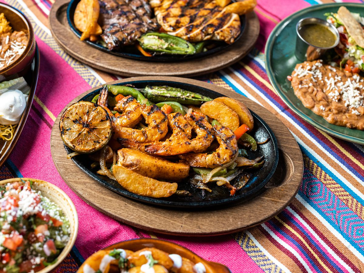 A colorful tablecloth sits under various Tex Mex dishes.