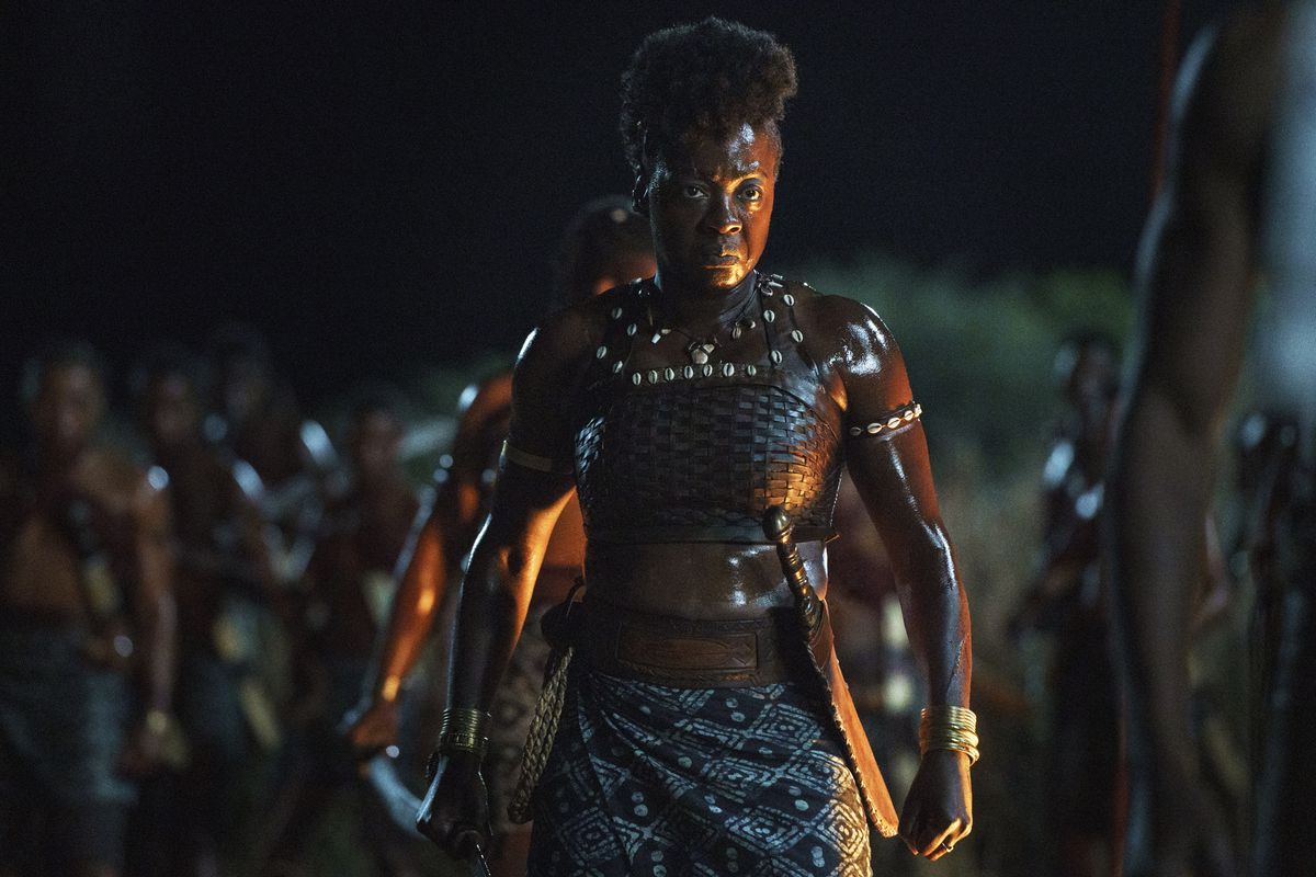 Viola Davis stands in a strong stance in warrior’s garb with a sword in The Woman King.