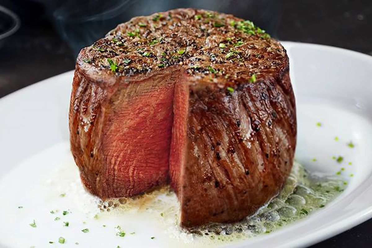 A steak filet that’s been cut into on a white plate.