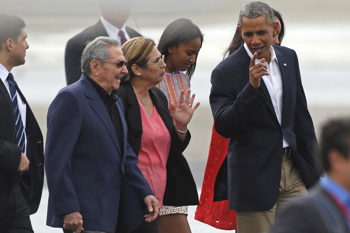 President Barack Obama, right, talks to Cuba's President Raul Castro, left, before boarding Air Force One on his way to Argentina, in Havana, Cuba, Tuesday, March 22, 2016. Behind are Obama's daughters Sasha, second from right, and Malia, partially covere