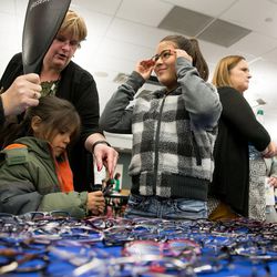 Yuliana Enriquez, 9, center, tries on glasses during SightFest at the Jordan School District Auxiliary Services building in West Jordan on Thursday, Dec. 8, 2016. SightFest is a partnership between Friends for Sight and the Utah Optometric Association that on Thursday provided free eye exams and glasses for 125 students from Title I schools in the Jordan School District.