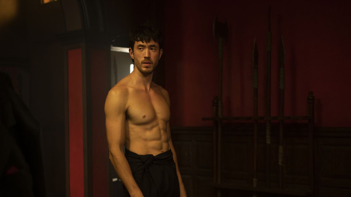 A shirtless Andrew Koji with ripped abs against a red background in Warrior.
