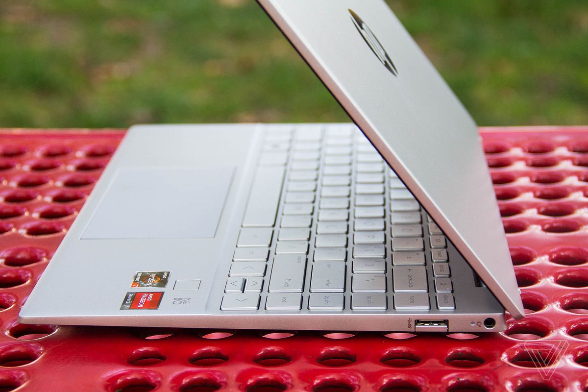 The HP Pavilion Aero 13 seen from the right, half open, on a red picnic table.