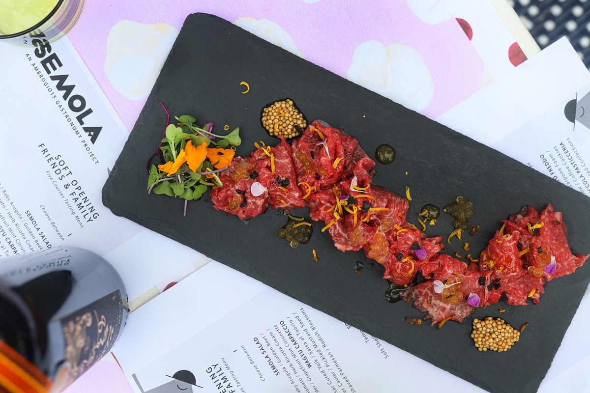 A rectangular black plate of wagyu beef carpaccio on a table at Semola