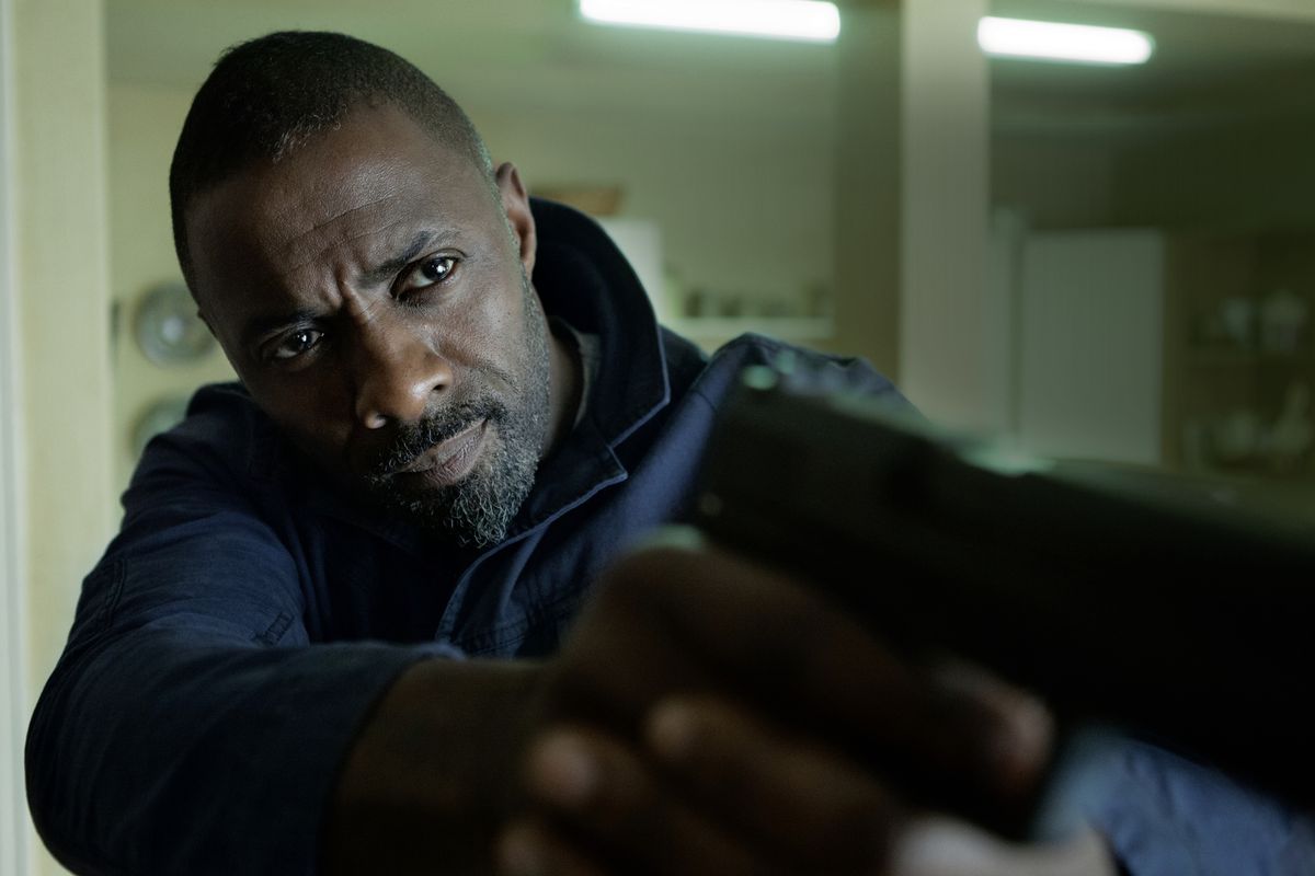 Idris Elba in The Take holding a gun at camera like he’s James Bond