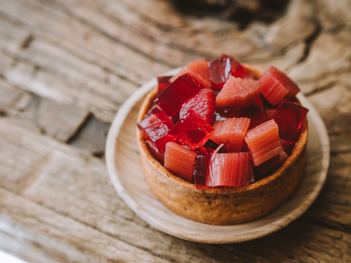 A tarte topped with rhubarb and jelly, on a wooden tabletop.
