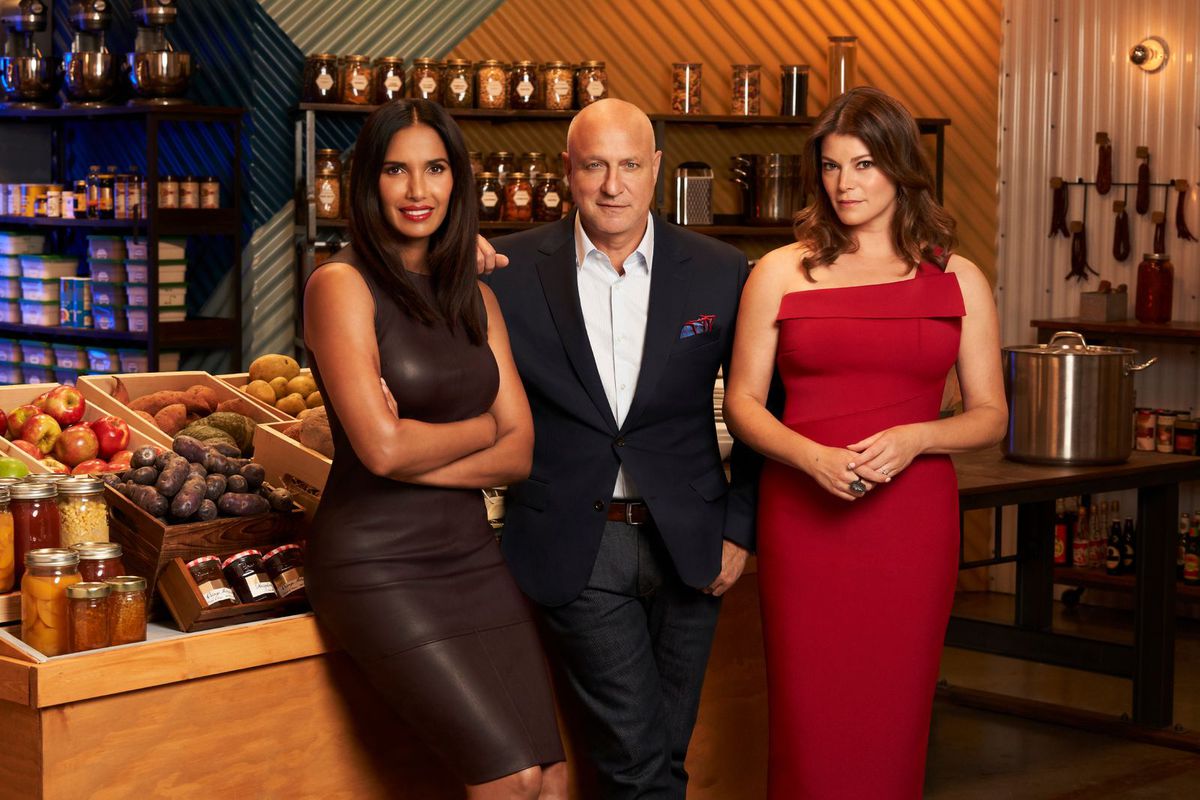 Padma Lakshmi, Tom Colicchio, and Gail Simmons stand in the grocery store set of Top Chef