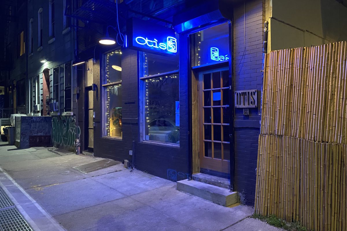 A storefront shot with blue neon lighting hanging above the door.