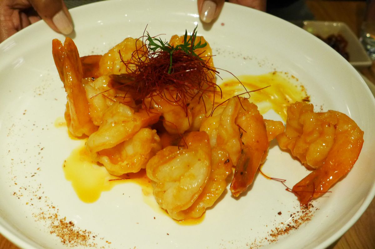 A number of pink shrimp are slicked with an orange colored sauce...
