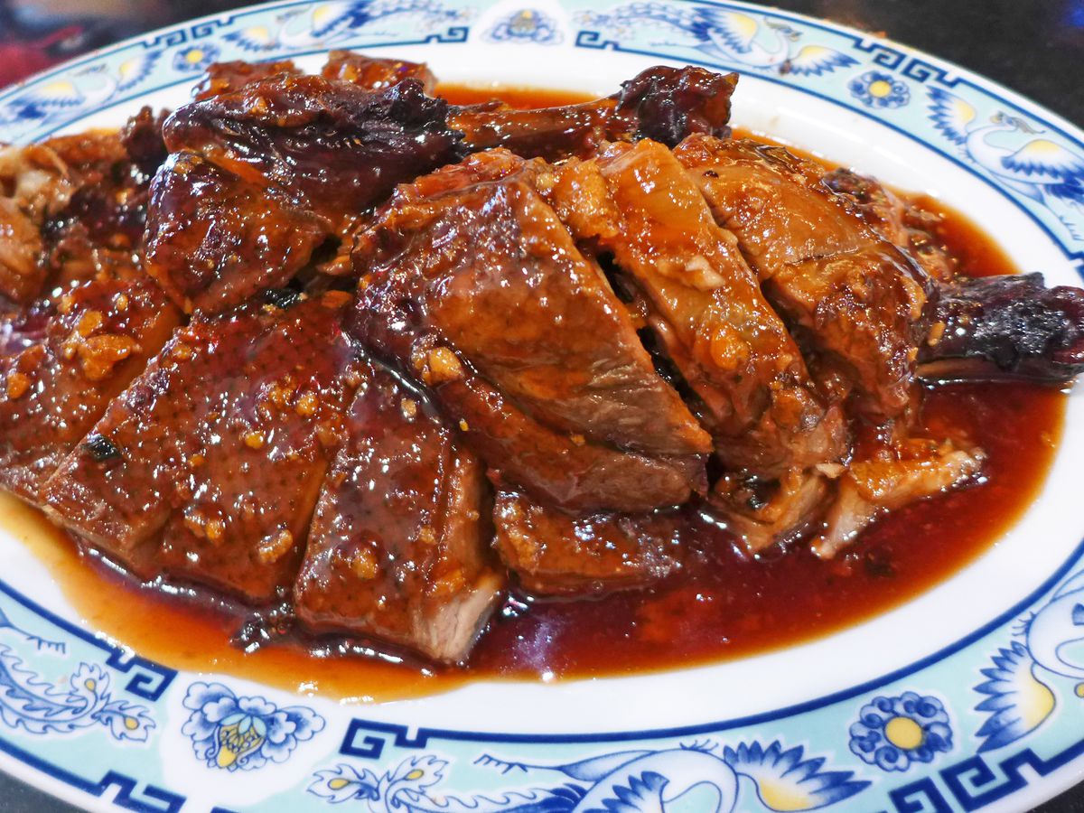 A blue delft platter of sliced duck in a thick orange sauce.
