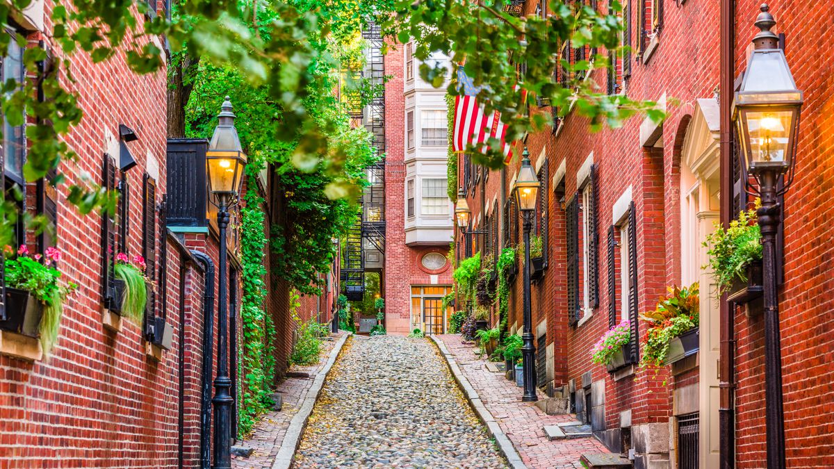 Acorn Street in Boston is lined with red brick houses, street lamps and trees.