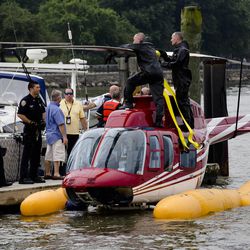 A helicopter rests on a pontoon at the 79th Street Boat Basin after an emergency landing over the Hudson river, Sunday, June 30, 2013, in New York.  New York authorities say a helicopter carrying four Swedish tourists landed in the Hudson River off Manhattan Sunday, but everyone has been rescued.